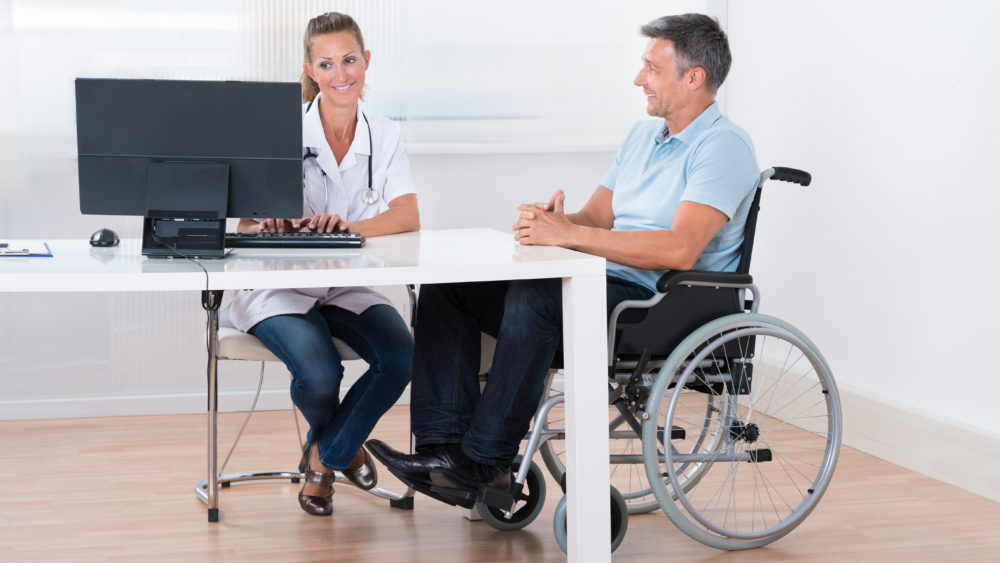 Man Sitting On A Wheelchair Consulting With Doctor