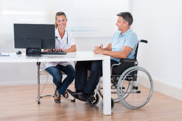 Man Sitting On A Wheelchair Consulting With Doctor