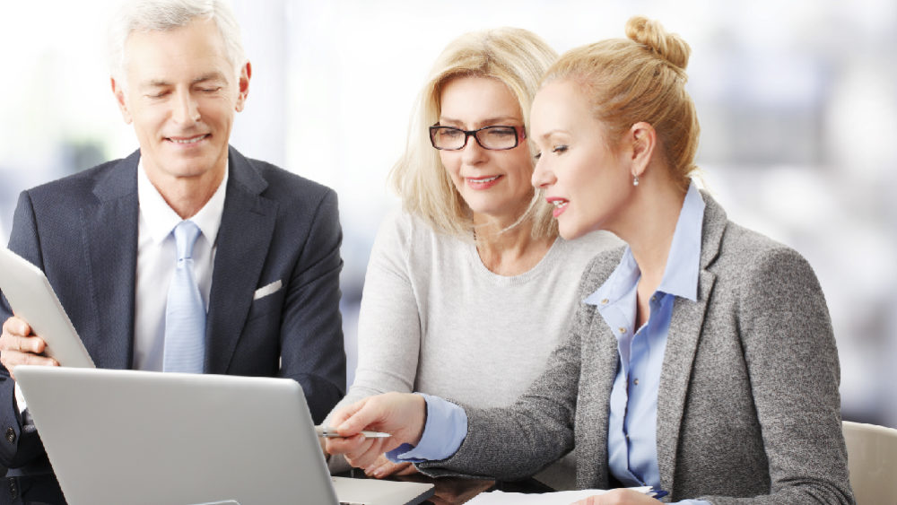 Man and two women seated around a laptop computer