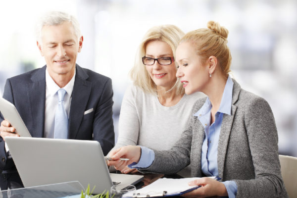 Man and two women seated around a laptop computer